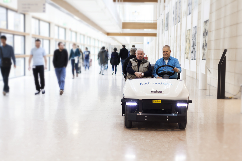 Een jonge medwerker in een winkel staat achter een tafel en vouwt denim broeken. Ze heeft een glimlach op haar gezicht.