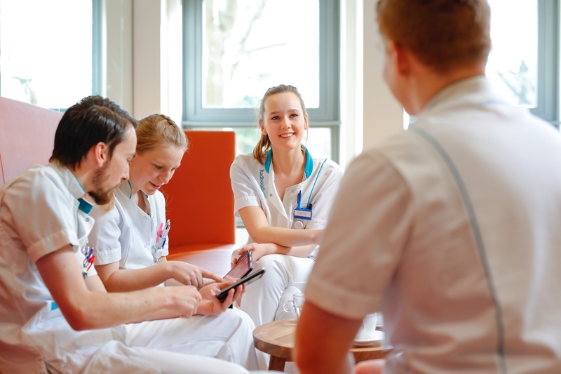 Een jonge medwerker in een winkel staat achter een tafel en vouwt denim broeken. Ze heeft een glimlach op haar gezicht.